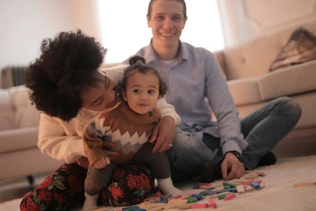 Happy family playing together indoors, representing safety, security, and the protection provided by roofing insurance.