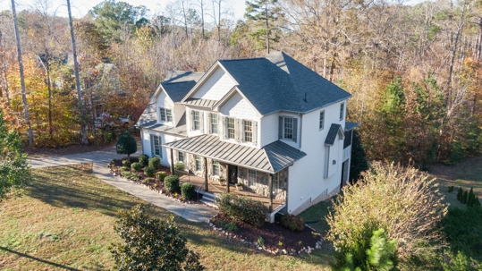 An aerial view of a beautiful two-story home surrounded by autumn trees, showcasing a well-maintained roof, perfect for residential roofing services in Tulsa, Oklahoma.