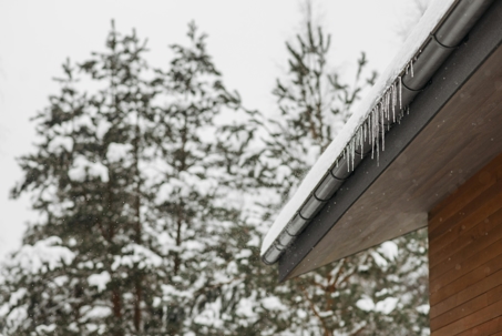 Gutters with icicles during winter, showing the importance of proper drainage and gutter maintenance to prevent water damage.